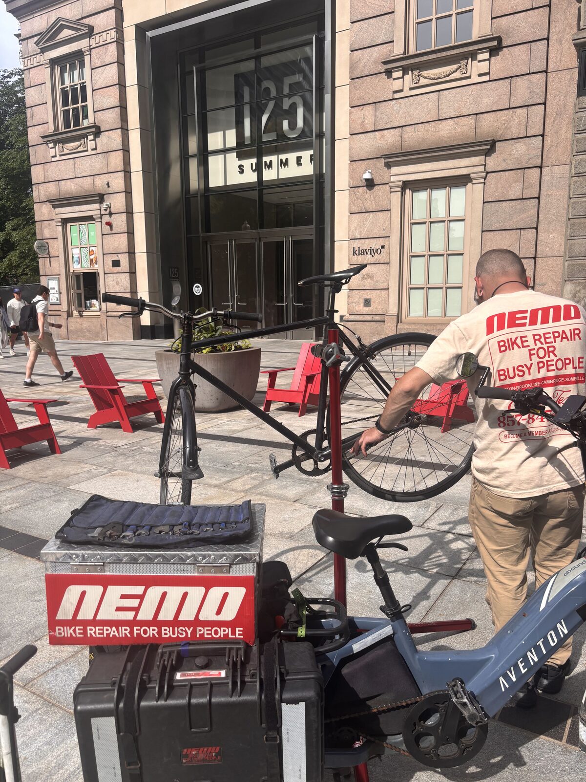 A NEMO mechanic helping a customer with their bike outside 125 Summer Street in downtown Boston